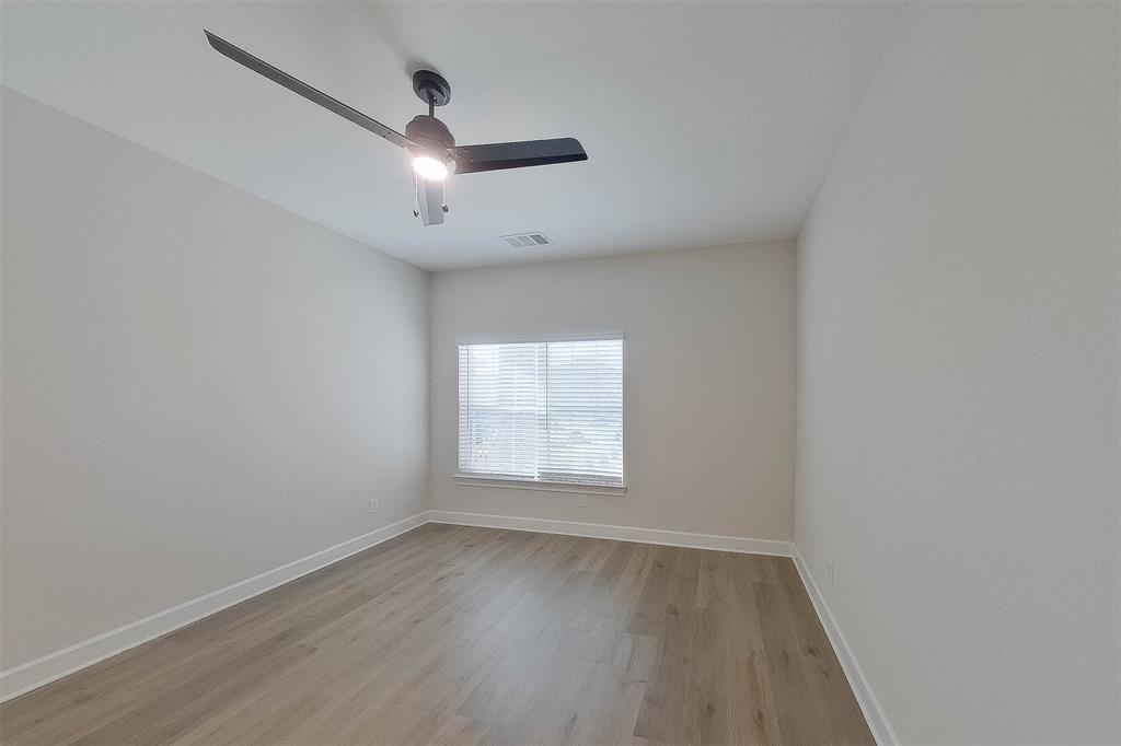 1206 Dye Boulevard Princeton, TX 75407 - Photo 11 of 29 an empty room with wooden floor ceiling fan and windows