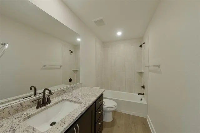 a bathroom with a granite countertop sink a toilet and shower