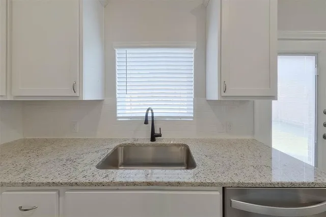a kitchen with granite countertop a sink and white cabinets