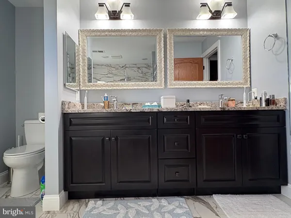 a bathroom with a granite countertop sink toilet and mirror