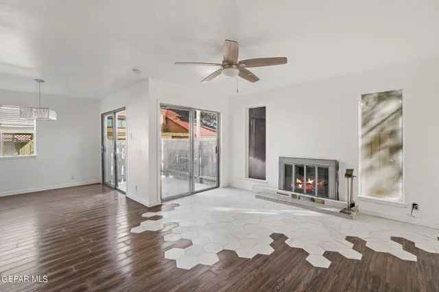 a view of an empty room with wooden floor a fireplace and a window