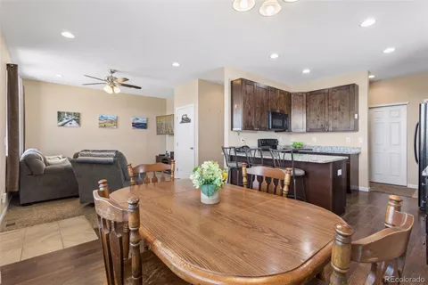 a kitchen with stainless steel appliances granite countertop a stove a refrigerator a sink a dining table and chairs