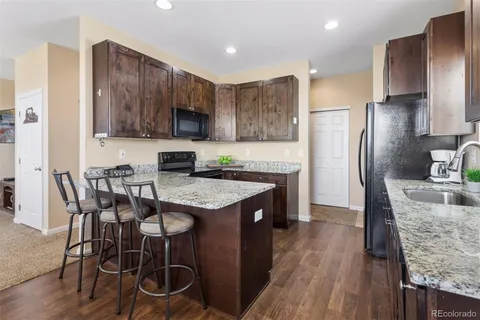 a kitchen with granite countertop a table chairs microwave and refrigerator