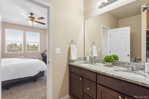 a en suite bathroom with a granite countertop sink and a large mirror
