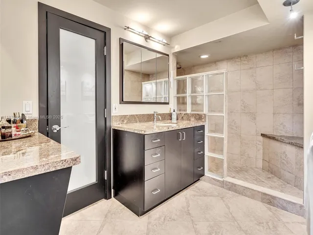 a bathroom with a granite countertop sink a toilet and shower