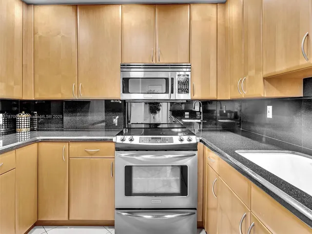 a kitchen with stainless steel appliances granite countertop a stove a sink and a microwave