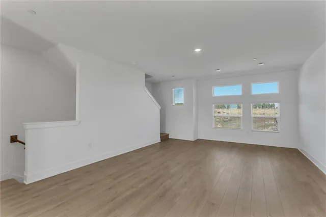 a view of a big room with wooden floor and windows