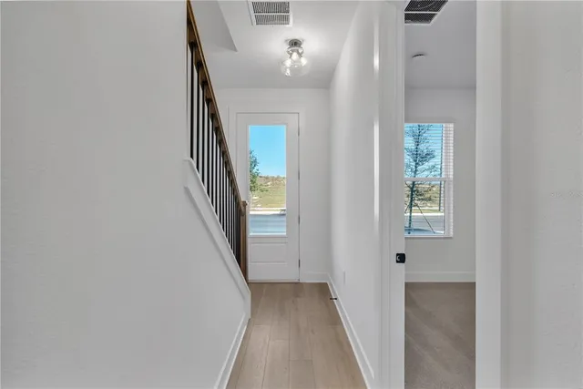 a view of a hallway with wooden floor and entryway
