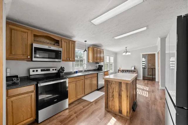 a large kitchen with stainless steel appliances granite countertop a stove top oven a sink dishwasher and a refrigerator