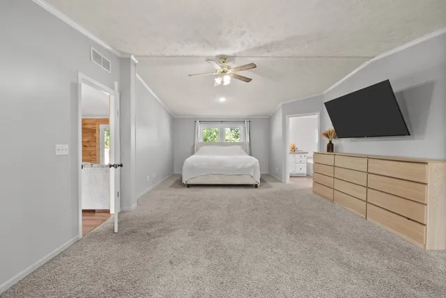 a spacious bedroom with a bed and a flat screen tv