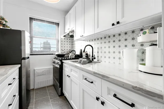 a kitchen with granite countertop a sink stove and refrigerator