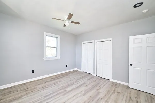 a view of empty room with wooden floor and fan