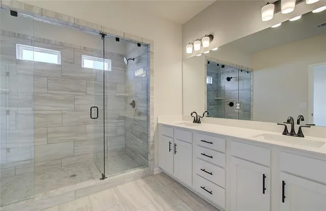 a bathroom with a double vanity sink mirror and shower