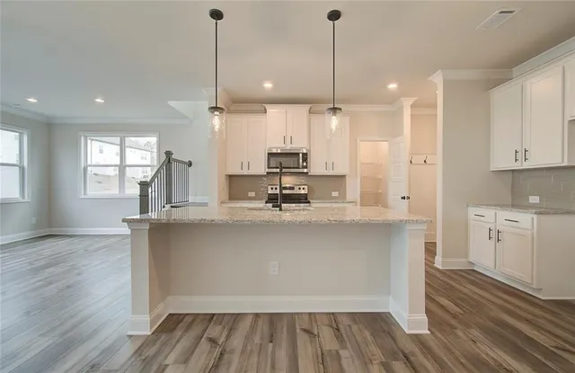 a kitchen with kitchen island white cabinets and stainless steel appliances