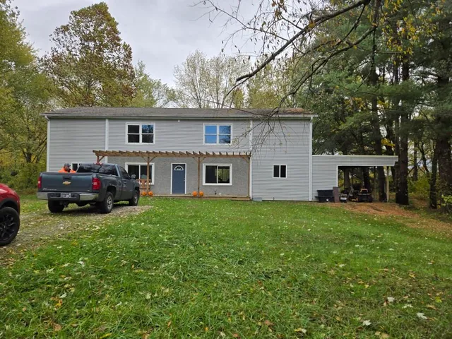 a view of a house with a big yard and large trees