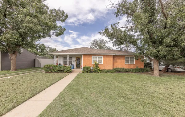 a front view of a house with a garden and trees