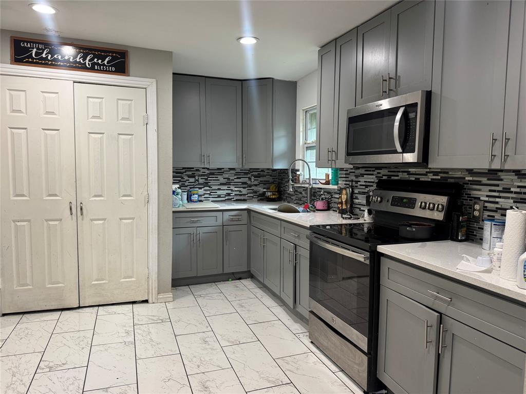 1104 Ridgeview Street Mesquite, TX 75149 - Photo 3 of 6 Kitchen featuring gray cabinets, light marble finish flooring, stainless steel appliances, backsplash, and light stone countertops