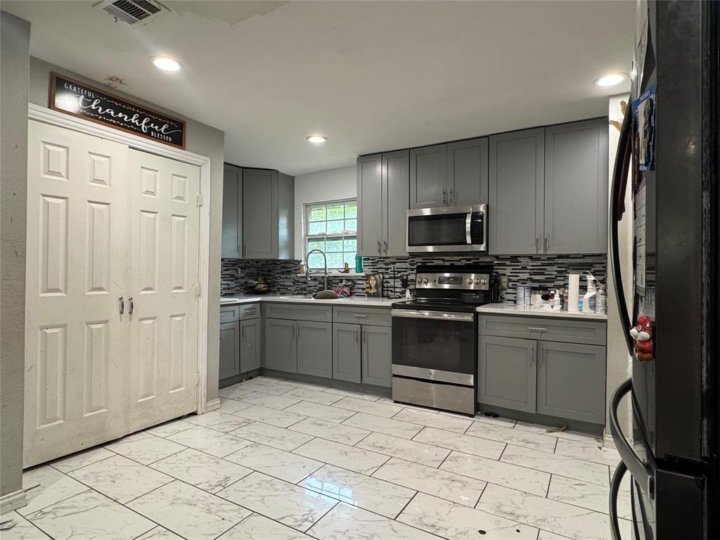1104 Ridgeview Street Mesquite, TX 75149 - Photo 4 of 6 Kitchen featuring gray cabinetry, appliances with stainless steel finishes, light marble finish floors, backsplash, and recessed lighting