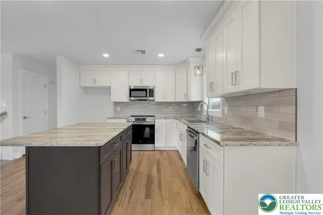 a kitchen with kitchen island granite countertop a sink stove and cabinets