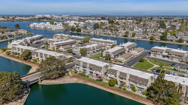 an aerial view of a city with lots of residential buildings ocean and mountain view in back