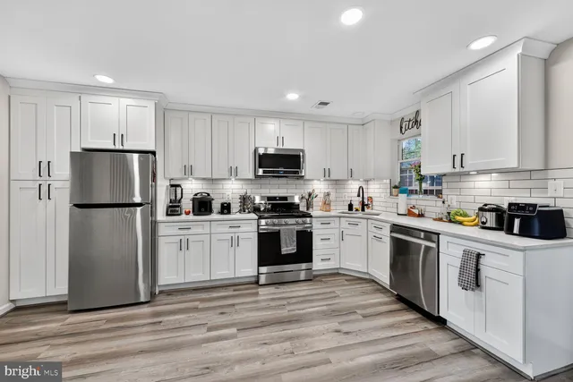 a kitchen with white cabinets and stainless steel appliances