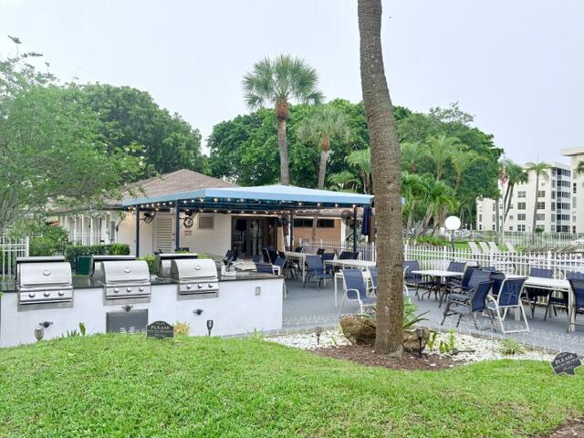 2671 South Course Drive, Unit 108 Pompano Beach, FL 33069 - Photo 21 of 40 a view of a patio with table and chairs potted plants and large tree