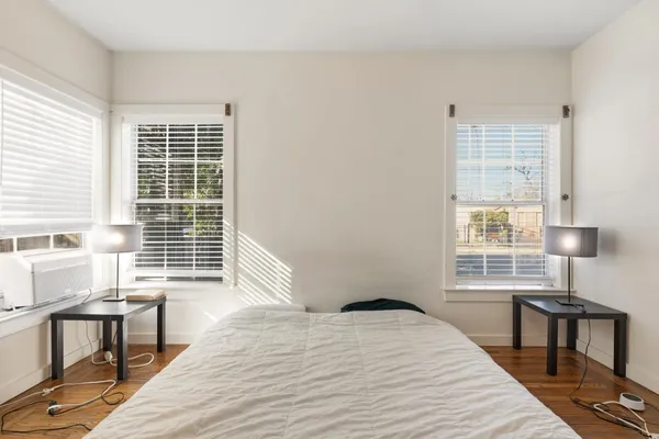 a bedroom with a bed windows and wooden floor