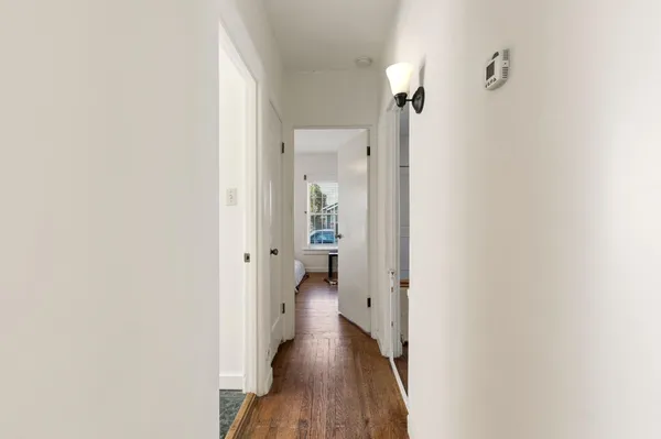 a view of a hallway with wooden floor and a bathroom