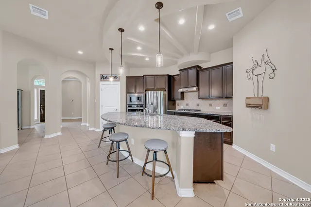 a kitchen with stainless steel appliances granite countertop a sink and a refrigerator