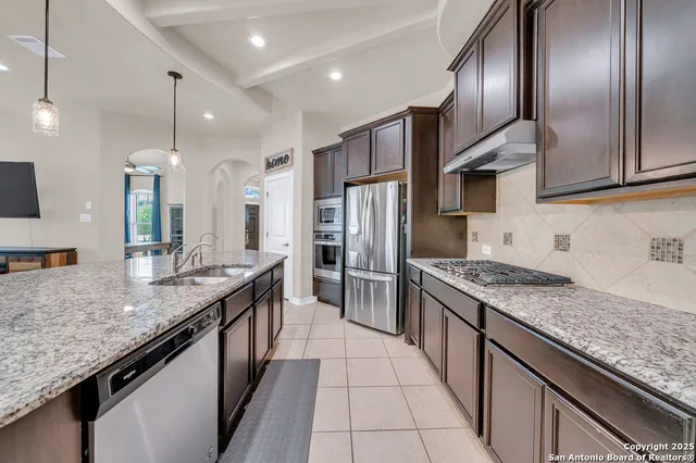a kitchen with stainless steel appliances granite countertop a sink a stove and a refrigerator