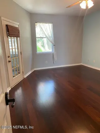 an empty room with wooden floor and windows
