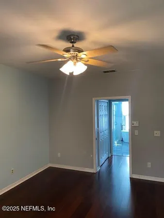 an empty room with wooden floor and chandelier fan