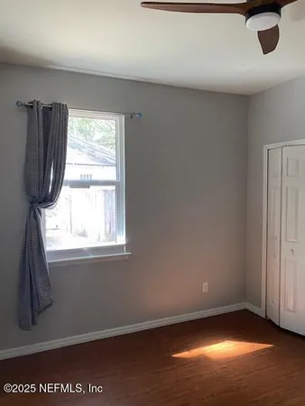 a view of an empty room with wooden floor and a window