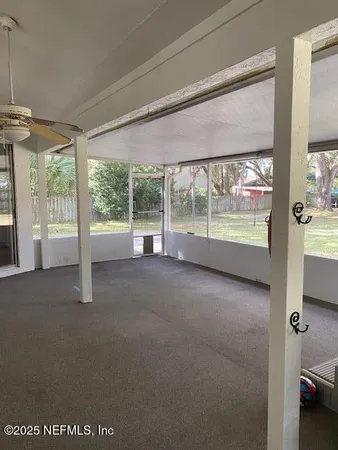 a view of empty room with floor to ceiling window and ceiling fan