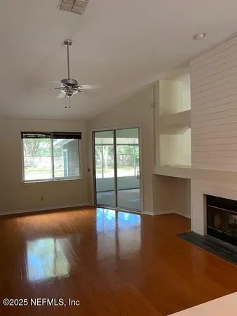 a view of empty room with wooden floor and fireplace