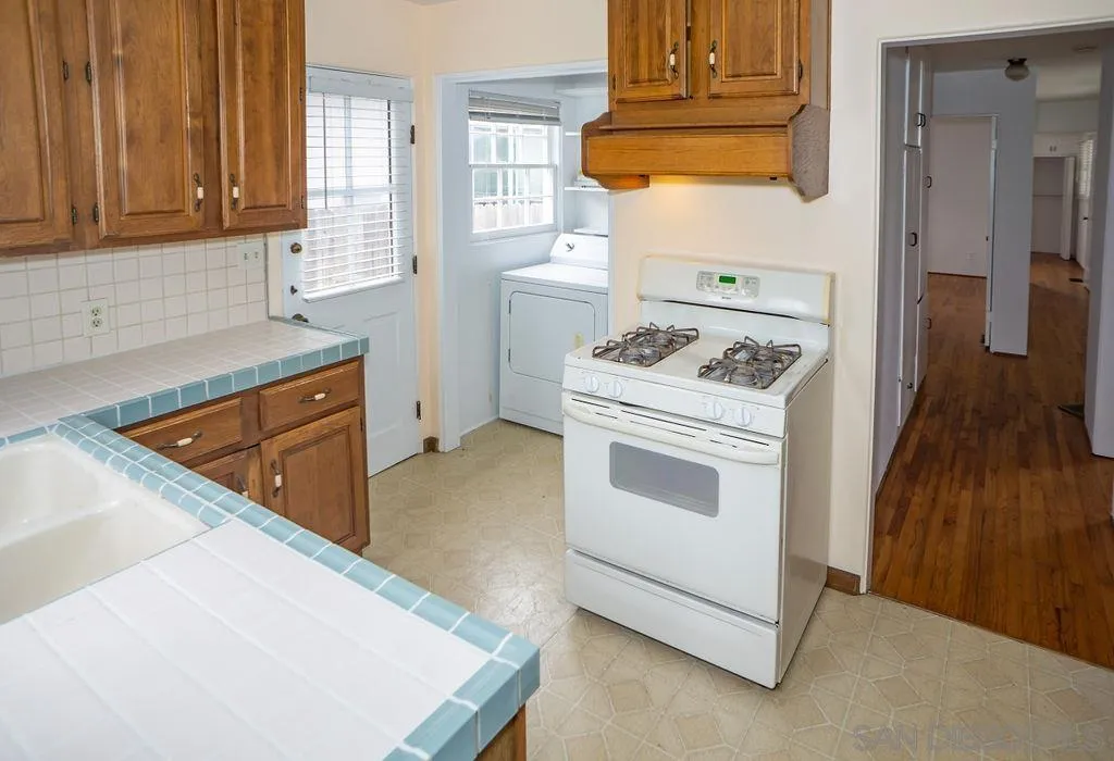 527 Forward Street La Jolla, CA 92037 - Photo 13 of 42 a kitchen with white cabinets and white appliances