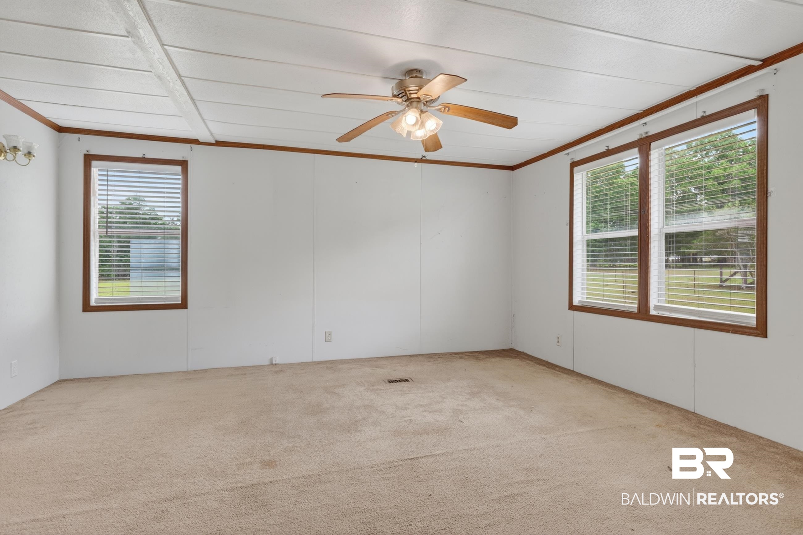 24903 Patterson Road Robertsdale, AL 36567 - Photo 39 of 57 Neutral tone walls featuring wood-tone trim, carpet flooring, a ceiling fan with integrated lighting, and multiple windows with blinds