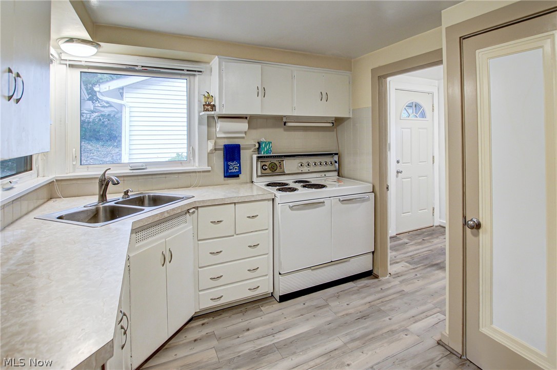 688 Wooster Road North Barberton, OH 44203 - Photo 5 of 47 Kitchen with sink, white electric range oven, backsplash, light hardwood / wood-style floors, and white cabinetry