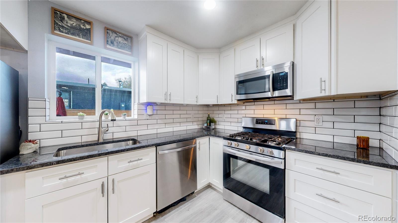9420 Ridge Road Arvada, CO 80002 - Photo 2 of 31 a kitchen with granite countertop a sink cabinets and stainless steel appliances