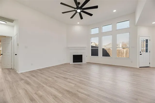 a view of a livingroom with a fireplace a ceiling fan and windows