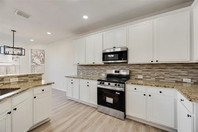 a kitchen with granite countertop a sink cabinets and stainless steel appliances