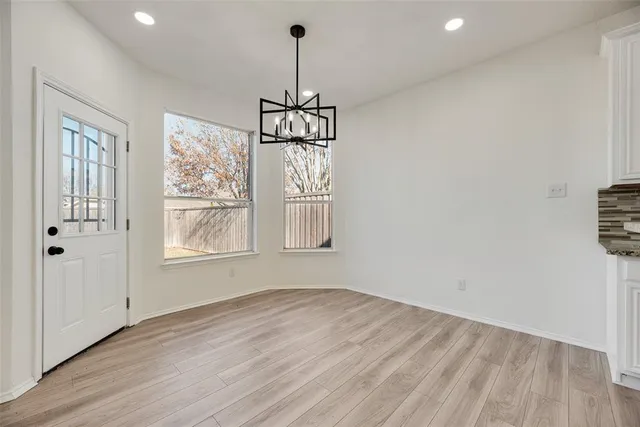 a view of an empty room with wooden floor and windows