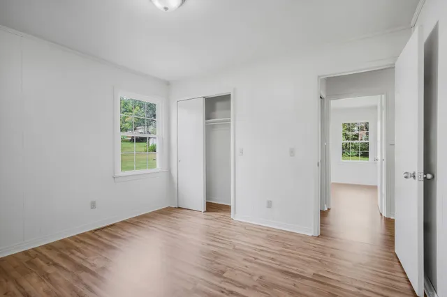 an empty room with wooden floor and windows