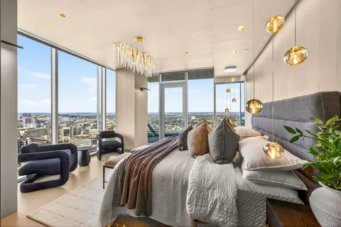 a bedroom with a bed a couch and large windows
