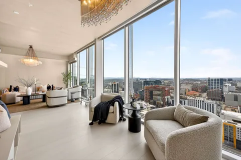 a living room with furniture wooden floor and floor to ceiling window