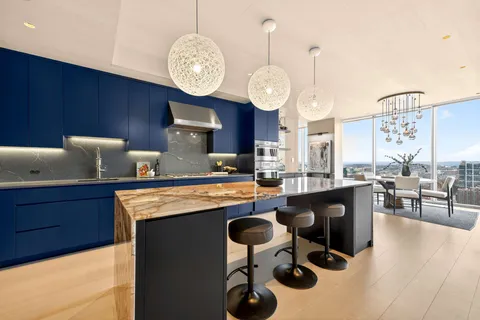 a large kitchen with stainless steel appliances granite countertop a stove a kitchen island a cabinets and a couch
