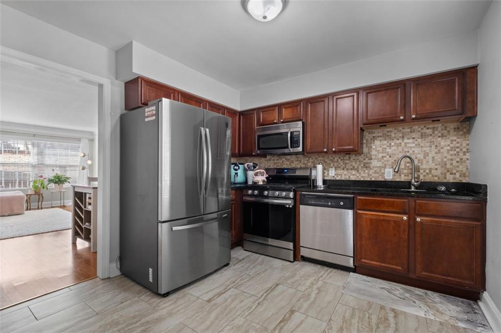 6980 Roswell Road, Unit A8 Atlanta, GA 30328 - Photo 5 of 26 a kitchen with granite countertop wooden floors stainless steel appliances and a counter space