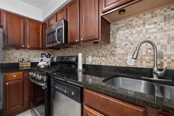 a kitchen with granite countertop a sink stove and cabinets