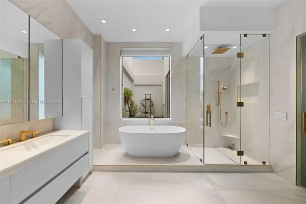a bathroom with a tub a sink and a large mirror