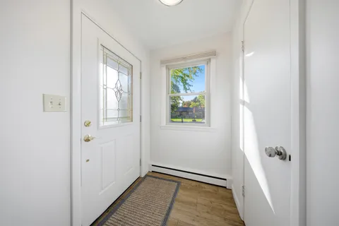 a view of an empty room with window and wooden floor